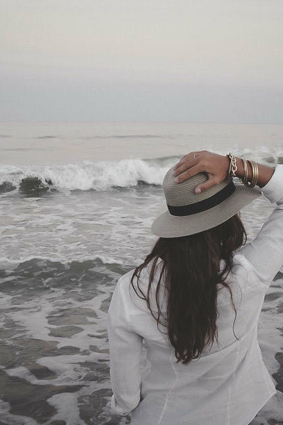 vrouw-hoed-zonnehoed-strand-zee-golven