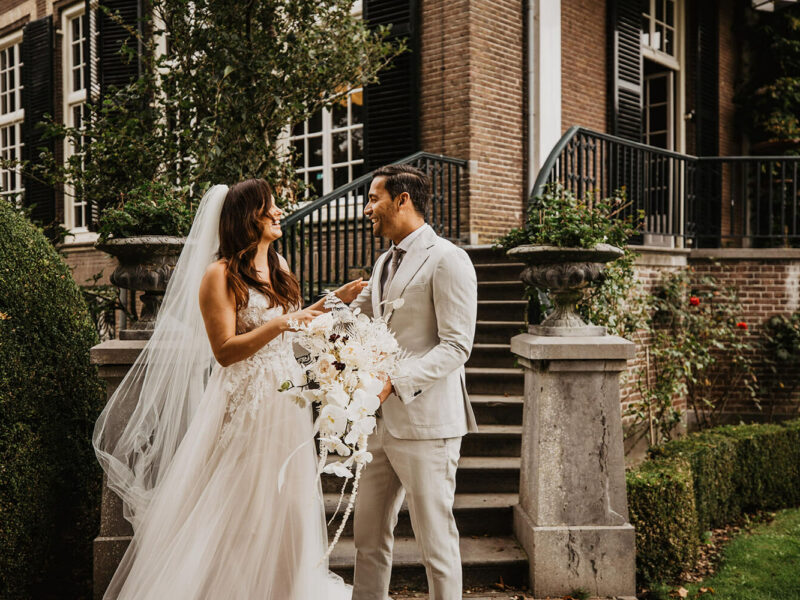 bruid en bruidegom zien elkaar voor het eerst – grijs trouwpak witte trouwjurk